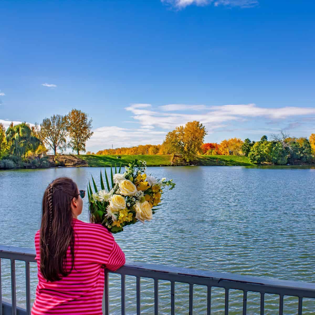 Person holding a white and yellow bouquet by the waterfront at LaSalle Rapids Park in Montreal