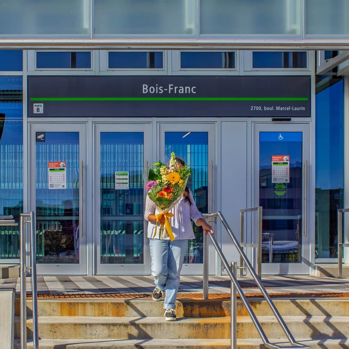 Person holding a colourful bouquet outside Bois-Franc REM station in Saint-Laurent