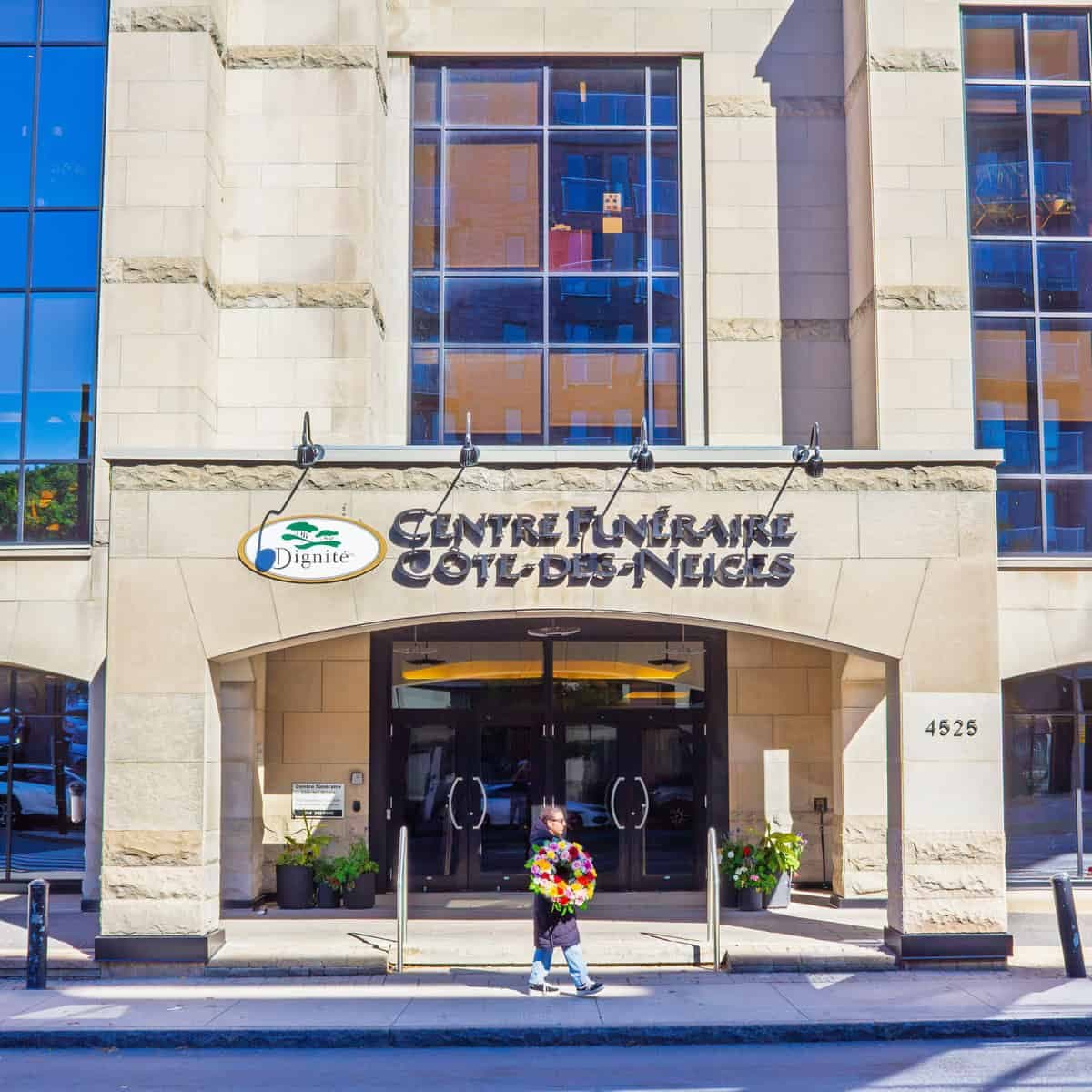 Person carrying funeral flowers outside Centre funéraire Côte-des-Neiges in Montreal