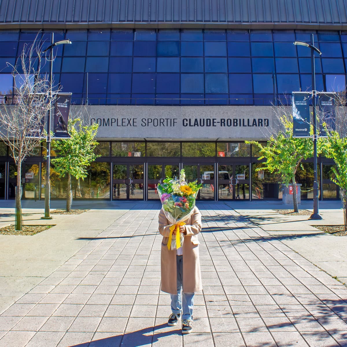 Person holding a colourful bouquet outside Complexe sportif Claude-Robillard in Ahuntsic-Cartierville