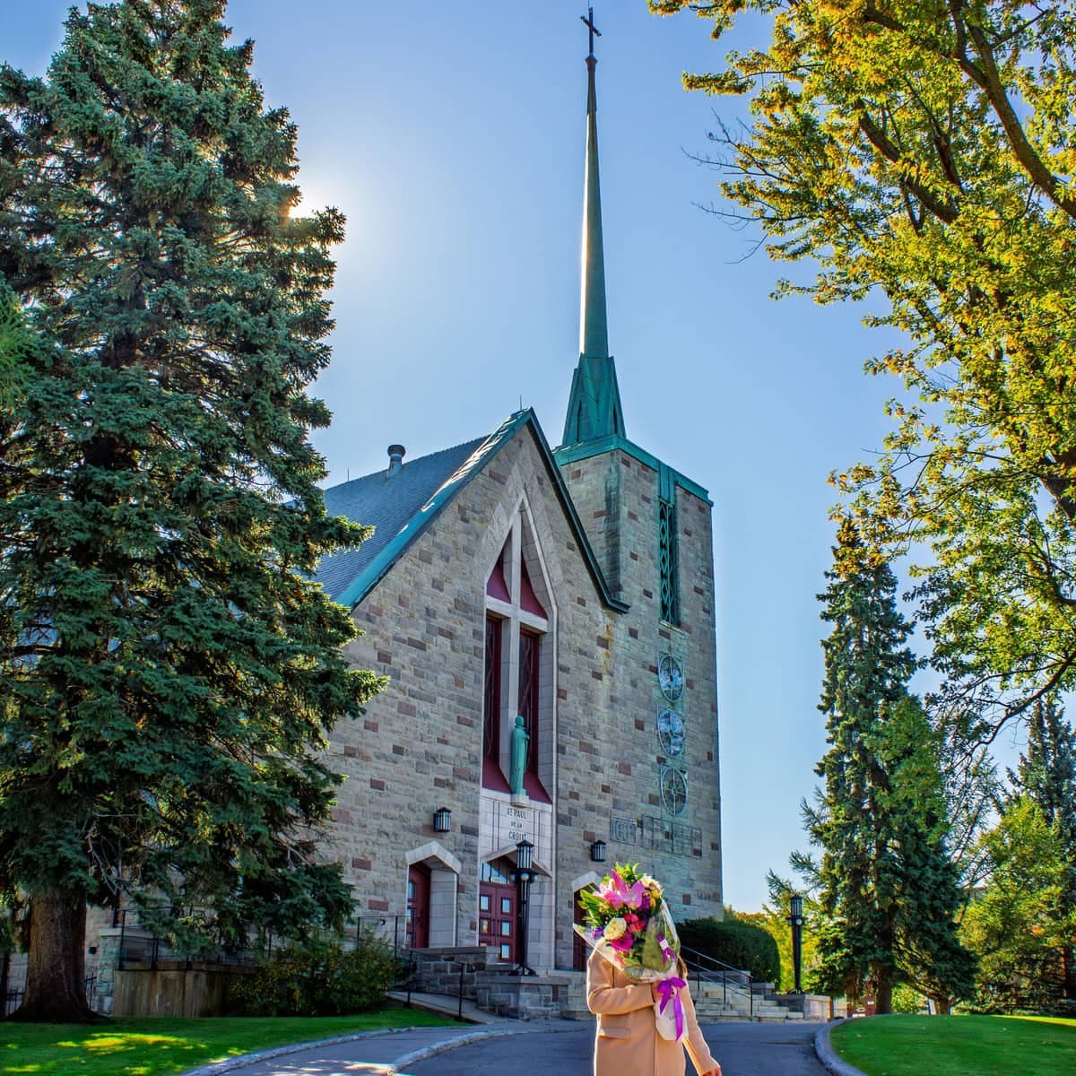 Person holding a colourful bouquet in front of Église Saint-Paul in Ahuntsic-Cartierville