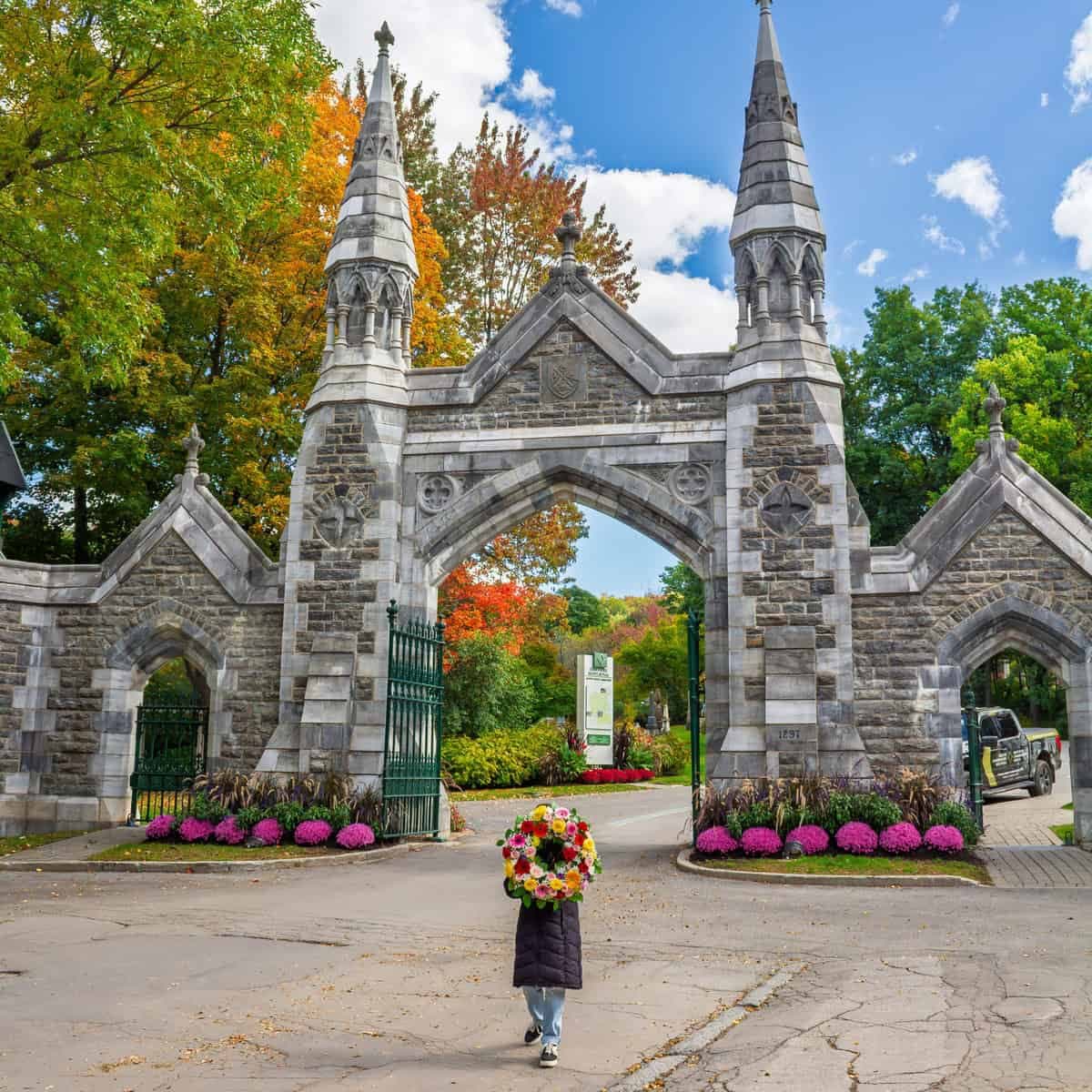 Person carrying a funeral wreath at the entrance to Mount Royal Cemetery in Outremont