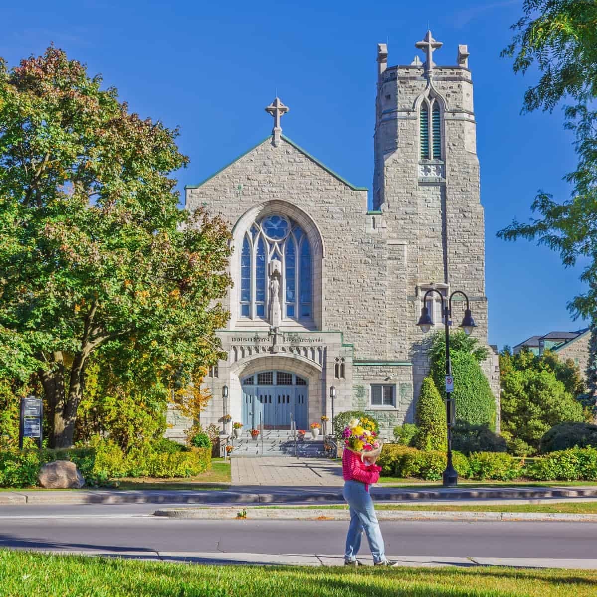 Person holding a colourful bouquet in front of Our Lady of the Annunciation Catholic Church in Town of Mount Royal