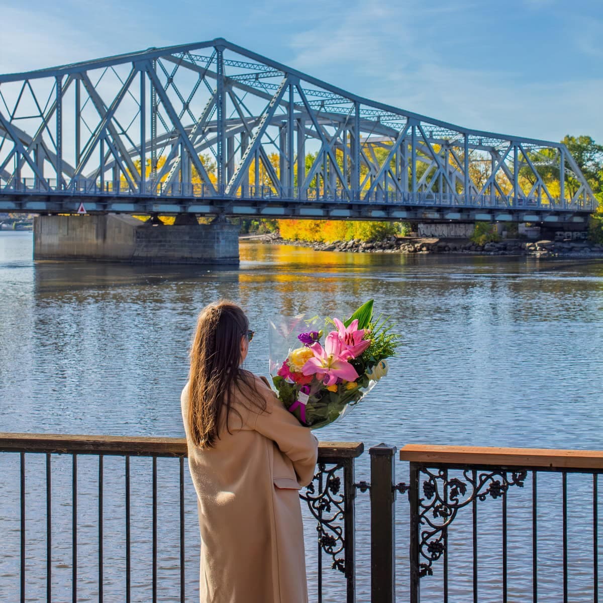 Person holding a colourful bouquet by the waterfront at Parc Belmont in Ahuntsic-Cartierville